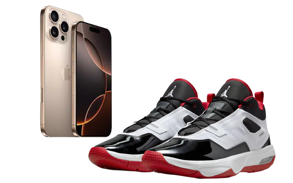 Home A gold iPhone 15 Pro Max model standing upright next to a pair of black, white, and red Jordan basketball shoes with red soles.